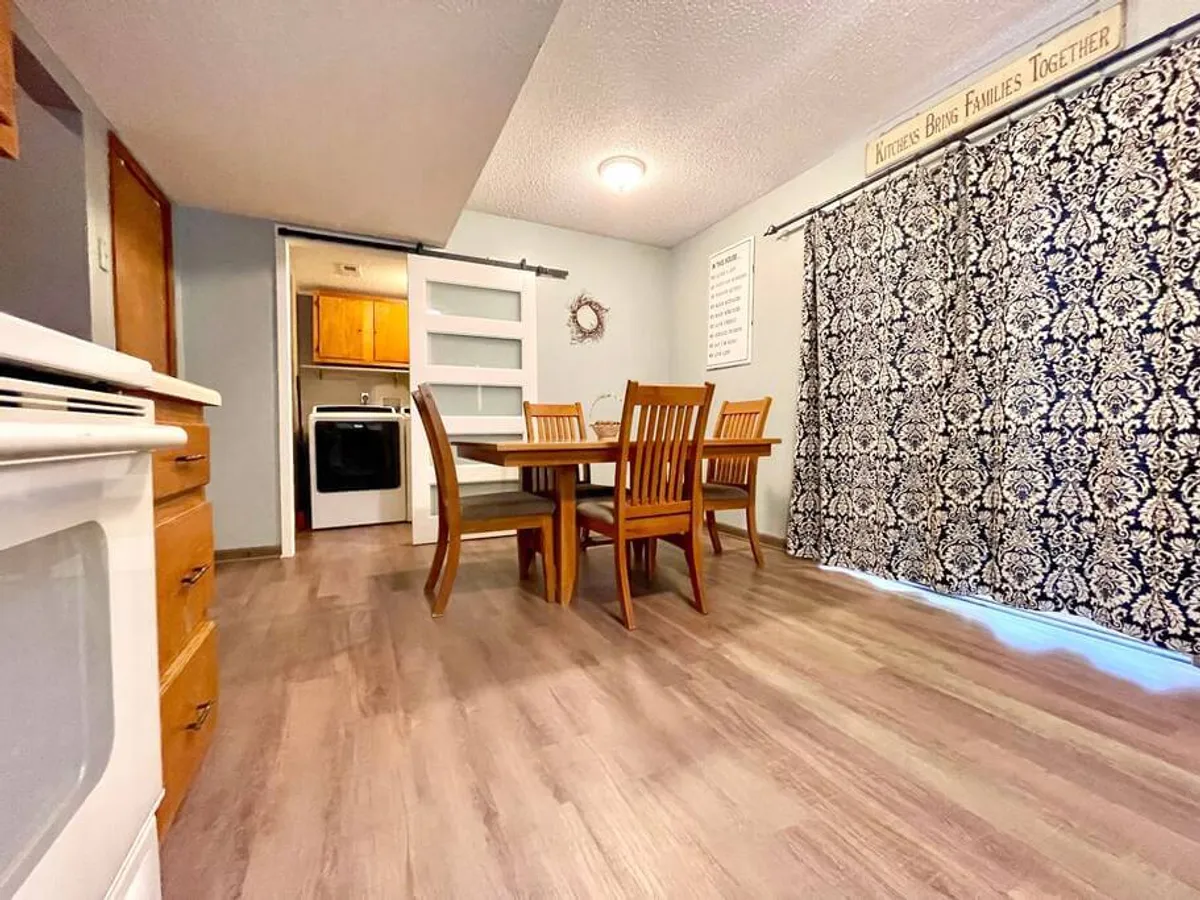 A cozy dining area with a central table and chairs, accented by curtains and wall décor. The scene suggests an intimate environment perfect for shared meals, conversations, or board game nights.