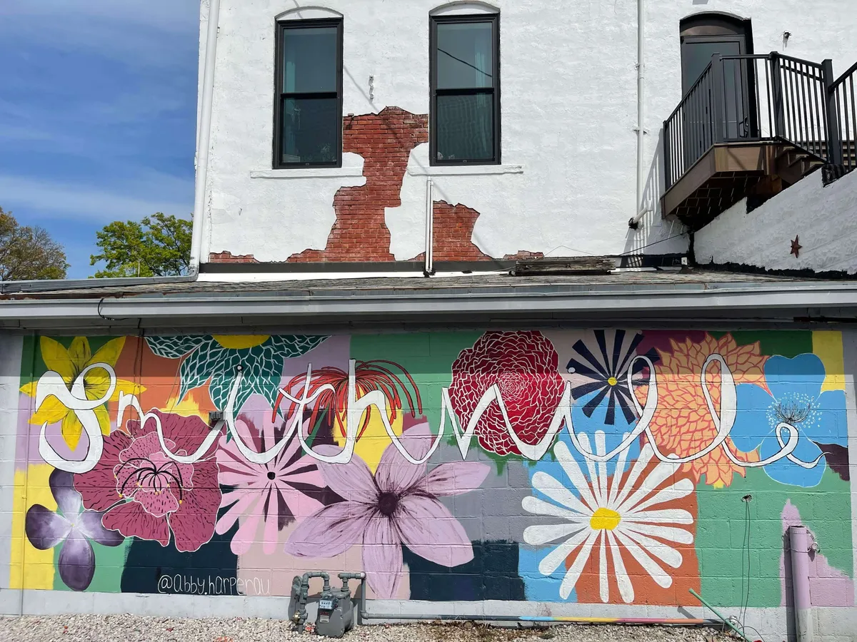 A bright exterior view of a building adorned with a cheerful, colorful mural. Large windows and a balcony hint at creative local culture, and the playful scene suggests opportunities for photography, art walks, and community gatherings.