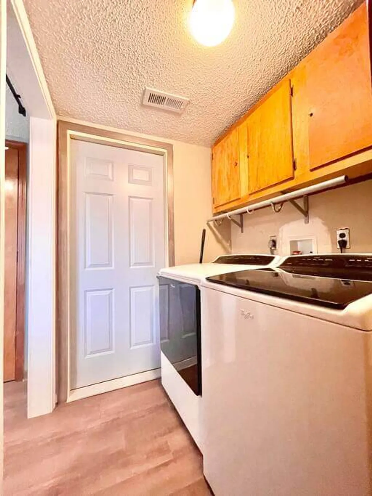 A clean, organized laundry area with a washing machine, dryer, and upper cabinets for storage. The design emphasizes practicality and tidiness, with closed cabinets providing concealed storage options.
